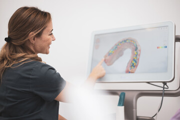 Fototapeta na wymiar Dentist woman showing patient on screen teeth after using 3d dental scanner, screen with 3d intraoral scan. Modern dentist concept.