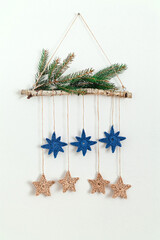 Christmas eco decor made of birch stick, crochet blue and beige stars and fir tree branches hanging...