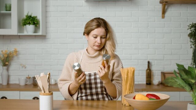 Housewife prepares dinner and chooses a jar of spices. Decision. Selection of spices in glass containers. Fragrant and aromatic dry crushed herbs. Spices will add expressiveness and richness of taste 