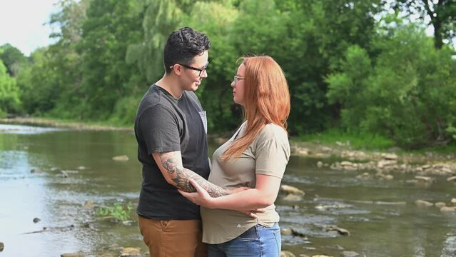 Pregnant woman embracing girlfriend outdoors.