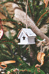 Vintage wooden toy house on Christmas tree. Natural Xmas ornaments for Christmas tree, zero-waste, closeup