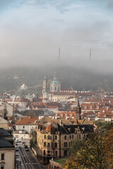 Prague panorama with historical buildings in foggy autumn morning,Czech Republic.View of Church of Saint Nicholas and Petrin Tower in mist.Amazing European cityscape.Travel architecture concept.