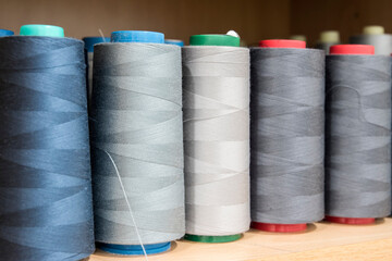 Sewing thread cones of different shade of colors on shelf in sewing studio closeup
