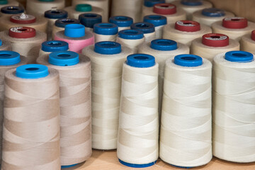 Sewing thread cones of different shade of colors on shelf in sewing studio closeup