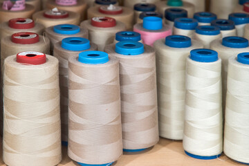 Sewing thread cones of different shade of colors on shelf in sewing studio closeup
