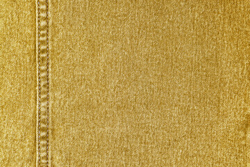 Denim jeans texture background. Texture of yellow colored cotton fabric with decorative seam....