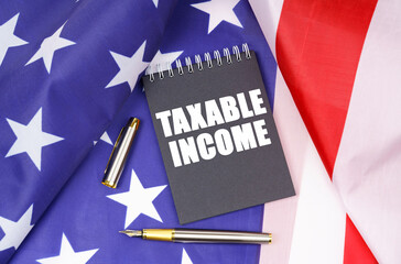 On the American flag lies a pen and a notebook with the inscription - taxable income