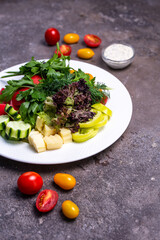 vegetables and greens on a white plate on a dark background