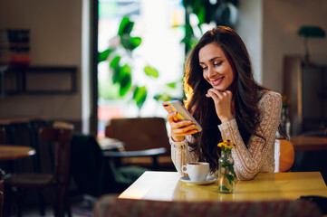 Portrait of beautiful young woman using smartphone in a cafe