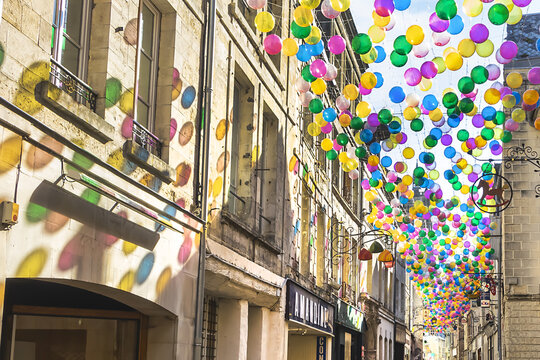 Narrow street with colorful balloons suspended over old town of Laon. Laon, Aisne, France. September 11, 2021.