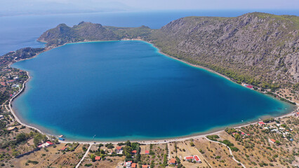 Aerial drone photo of scenic lake Vouliagmeni in Corinthia near famous lighthouse of Heraion and city of Loutraki featuring crystal clear turquoise beach and calm waters, Perachora, Greece