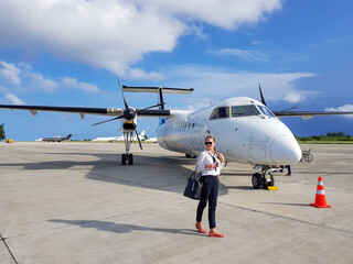 woman in business attire standing on airfield next to private jet plane. Luxury business trip,...