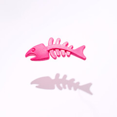 Fish bones, neon pink pet's toy, minimal creative layout against white background. 