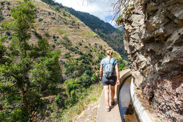 Young woman on hiking trail along Levada Nova hike tour on Madeira island in Portugal