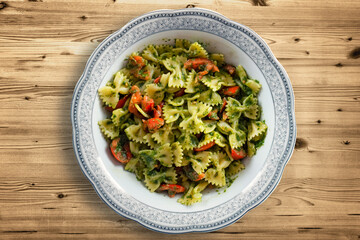Delicious pesto pasta dish seen from above. Typical genoese dish. Concept of italian cuisine and mediterranean diet. Pasta topped with cherry tomatoes and pesto.