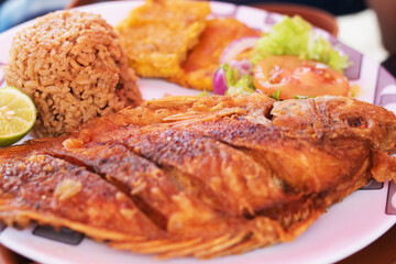 delicious fried mojarra with coconut rice, salad and patacones on the seashore, typical food of the colombian caribbean coast, cartagena de indias