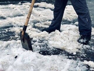A worker breaks snow on the road with a shovel.