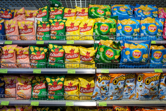 Various brands of potato chips Lay's, Estrella, and Cheetos on shelf in a grocery store. Minsk, Belarus, 2022