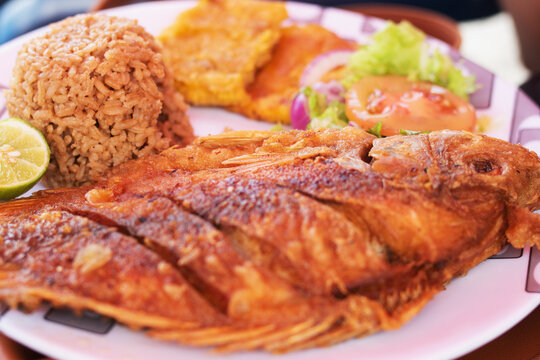 delicious fried mojarra with coconut rice, salad and patacones on the seashore, typical food of the colombian caribbean coast, cartagena de indias