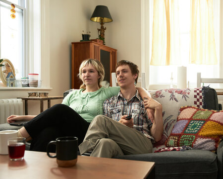 Non Binary LGBTQ+ Couple sitting on couch relaxing - Powered by Adobe