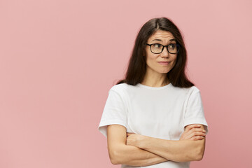 Fototapeta premium portrait of a cute, attractive brunette in a white tank top on a pink background, with a pleasant smile, standing in glasses for vision