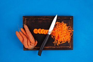 Deformed conjoined carrot and knife on cutting board, top view. Ugly vegetable abnormal shape....