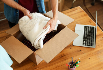 Top down view of man packing clothes into cardboard boxes to send it to client 