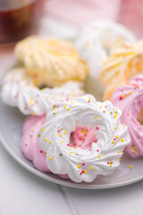 Different colors meringues with sprinkles on plate.