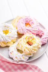 Fototapeta na wymiar Different colors meringues with sprinkles on plate.