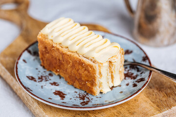 French dessert called Mille Feuille or Napoleon cake on rustic wooden board. Layered tasty cake with vanilla cream and puff pastry.