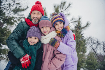 Photo of cheerful full family cuddle enjoy each other walking free time woods snowfall outside