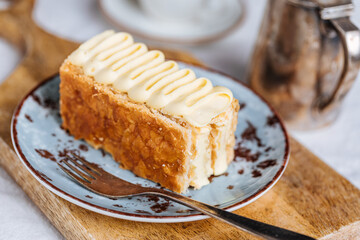 French dessert called Mille Feuille or Napoleon cake on rustic wooden board. Layered tasty cake...