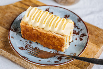 French dessert called Mille Feuille or Napoleon cake on rustic wooden board. Layered tasty cake with vanilla cream and puff pastry.
