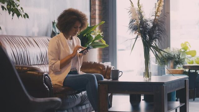 Focused African American businesswoman texting on smartphone in a coffee shop