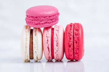 Close up of Macaroons in different colours on bright white background with subtle reflection on marble tray. Popular merengue dessert with filling inside. 