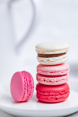Close up of Macaroons in different colours on bright white background with subtle reflection on marble tray. Popular merengue dessert with filling inside. 