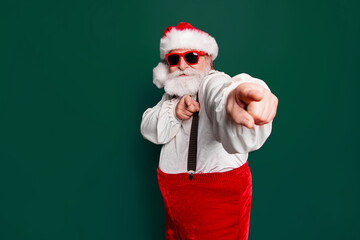 Fototapeta na wymiar Portrait of stylish trendy happy joyful funky funny confident Santa pointing at camera prepared ready to feast festive party promo sale discount isolated over red background