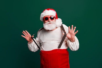 Fototapeta na wymiar Portrait of cheerful positive dreamy funky Santa congratulations best wishes pulling suspenders ready to feast congrats isolated over bright vivid red background