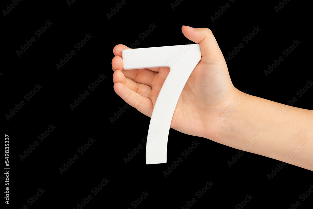 Aufkleber Number seven in hand isolated on black background. Number 7 in a child's hand on a black background. To be inserted into a project or design.