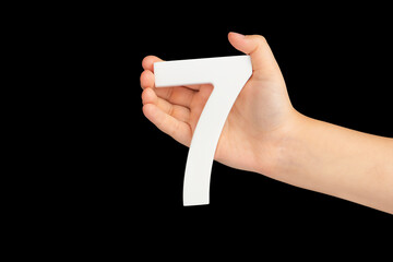 Number seven in hand isolated on black background. Number 7 in a child's hand on a black...