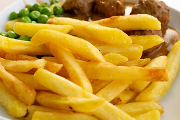 Meatballs with French Fries, Green Peas, Bechamel Sauce on White Plate