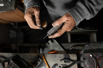 A craftsman jeweler is adjusting the drill to craft a jewel