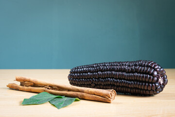 Maíz morado y canela en rama sobre superficie clara