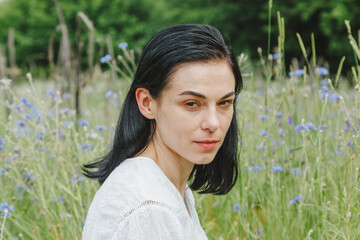 Beautiful girl among the summer field with wildflowers