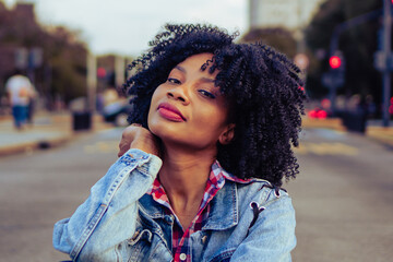young black haitian woman with afro hair looks into the camera with an urban look