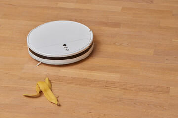 Robotic vacuum cleaner on laminate wood floor smart cleaning technology. banana