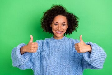 Photo of toothy beaming stylish girl with wavy hairstyle dressed blue pullover showing thumbs up isolated on green color background