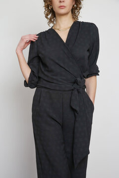 Series of studio photos of young female model in black linen outfit. 