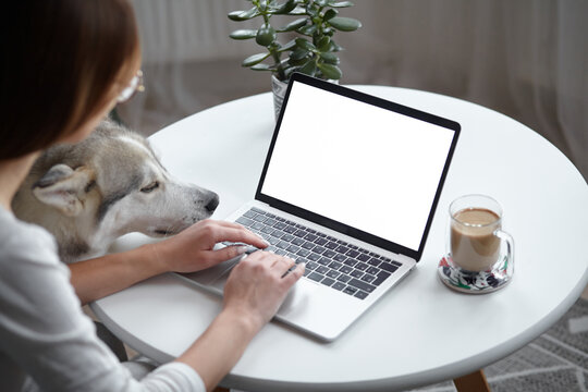 Mockup white screen laptop woman with a pet dog using computer while sitting at table at home, back view