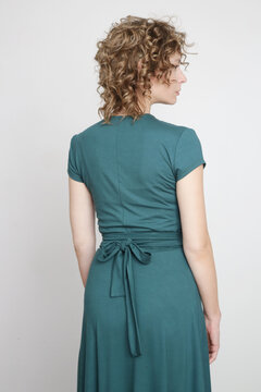 Serie of studio photos of young female model in green viscose wrap dress.